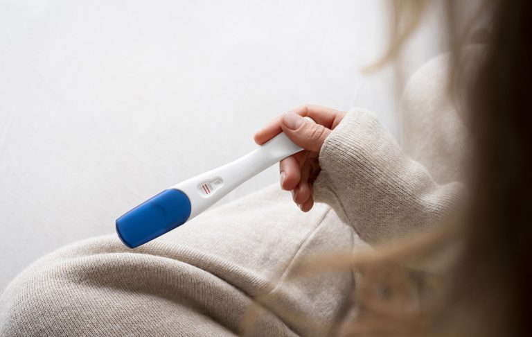 vue laterale femme tenant un test de grossesse positif