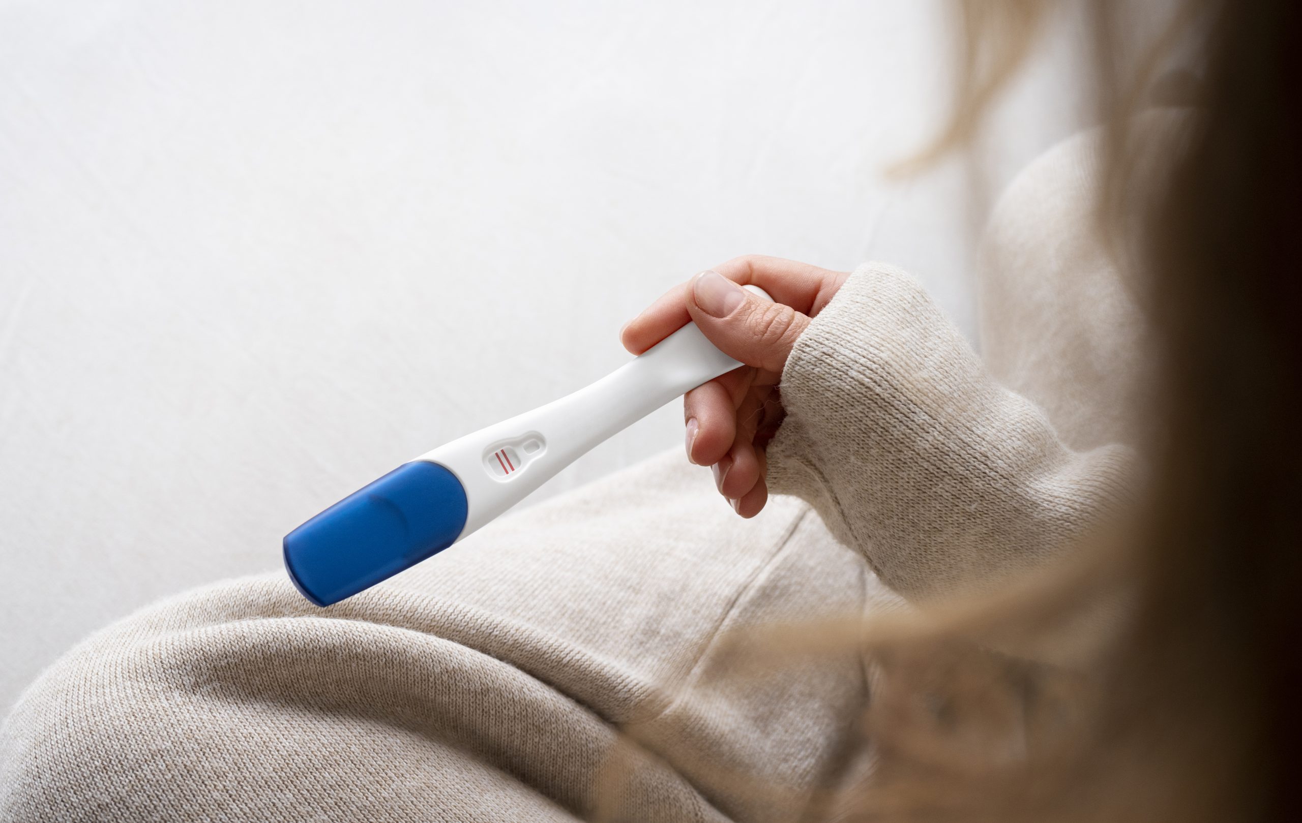 vue laterale femme tenant un test de grossesse positif